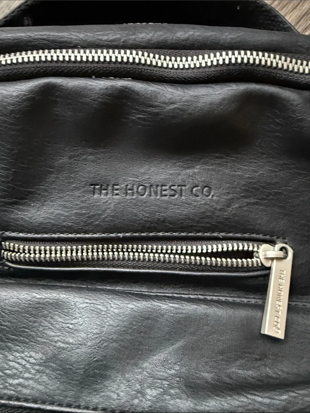 The Honest Company Black Vegan Leather Diaper Bag backpack model cross country